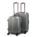 Two dark grey suitcases with wheels on a white background