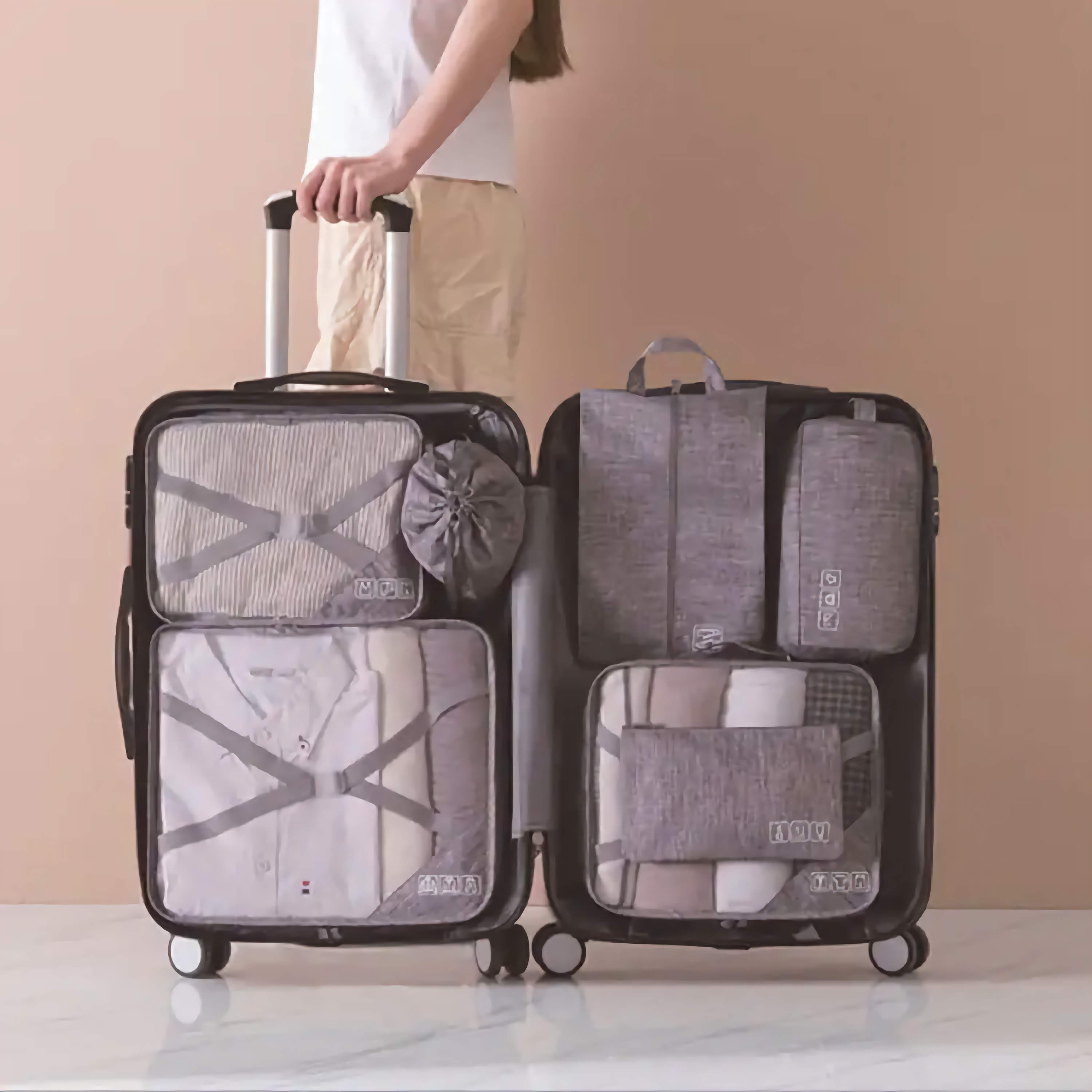 Person holding a suitcase with packing cubes on a beige background