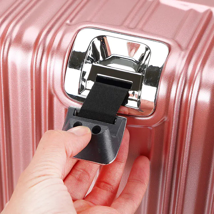 Hand pulling a black luggage strap attached to a pink suitcase.