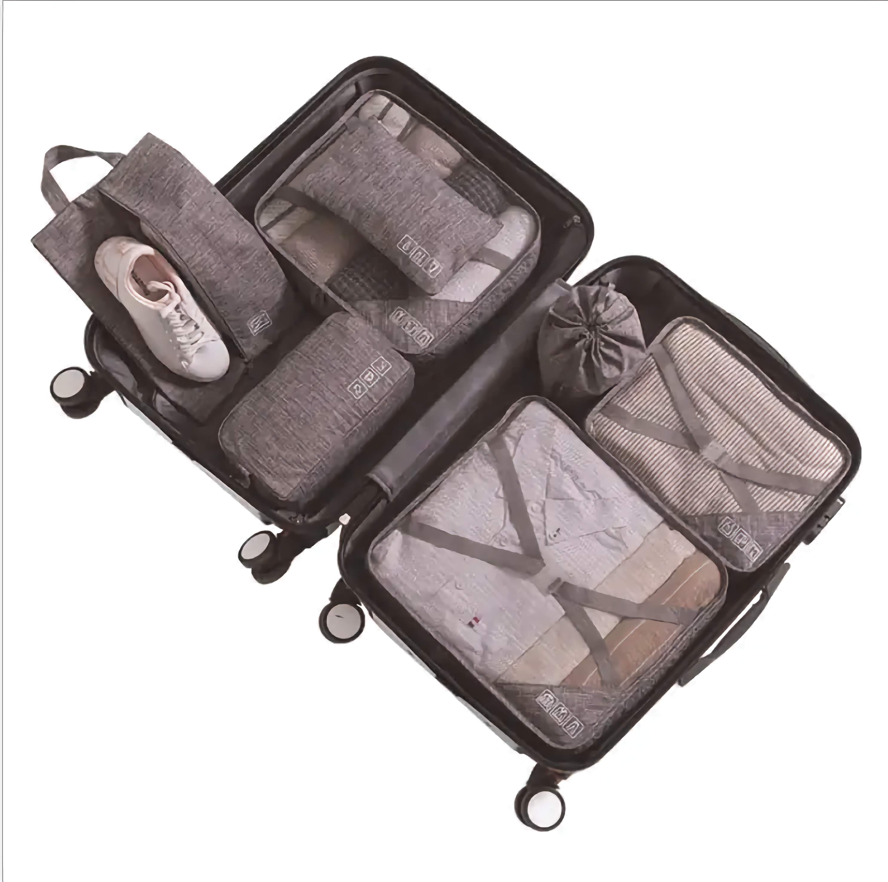 Set of grey travel packing cubes with clothes inside on a white background