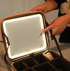 Person holding a makeup bag with a mirror inside, illuminated by LED lights.